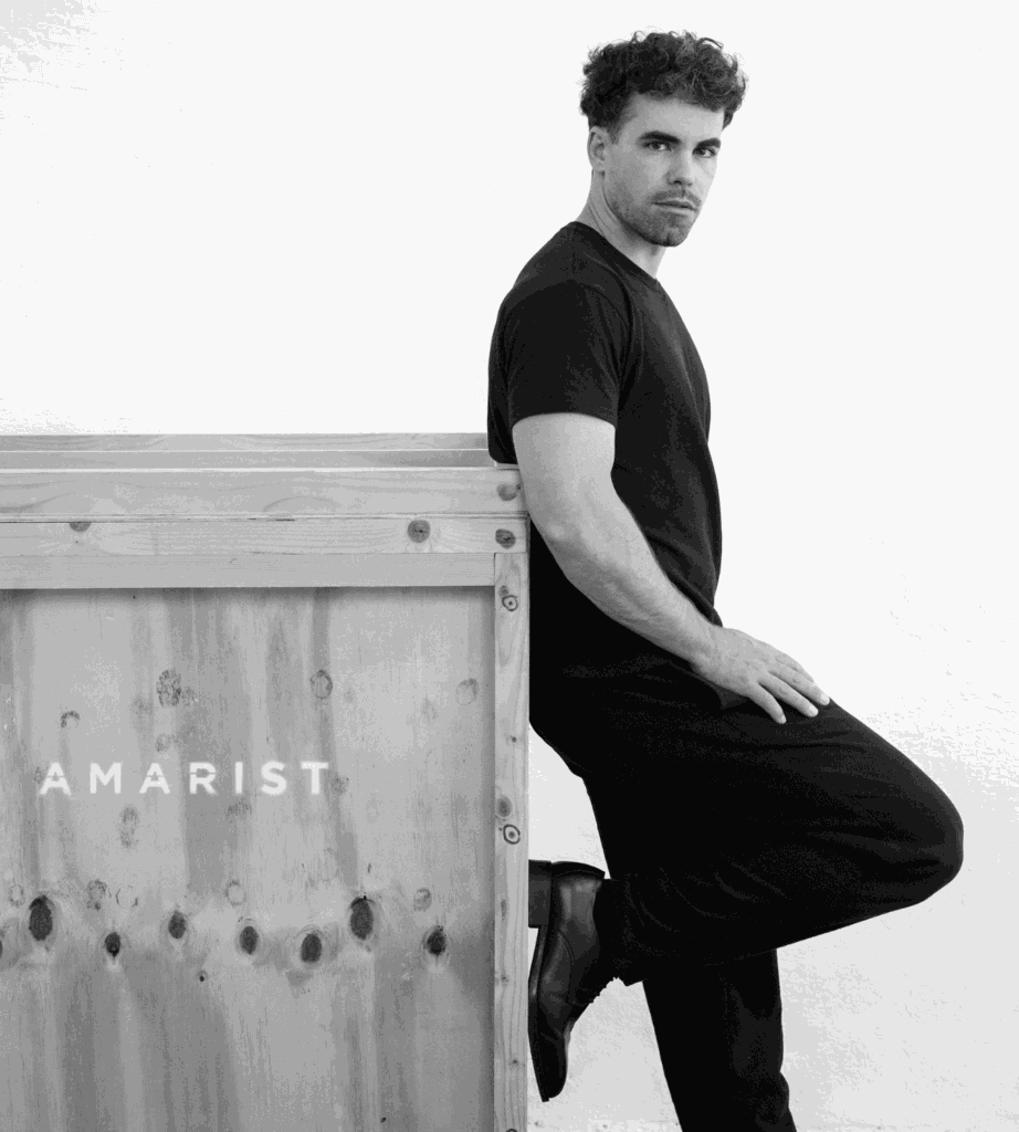 Aran Lozano en su espacio de trabajo, retratado de cuerpo entero en blanco y negro