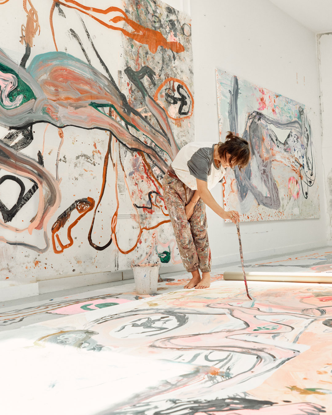 Jedda-Daisy Culley durante el proceso de creación de sus pinturas, rodeada de sus obras.