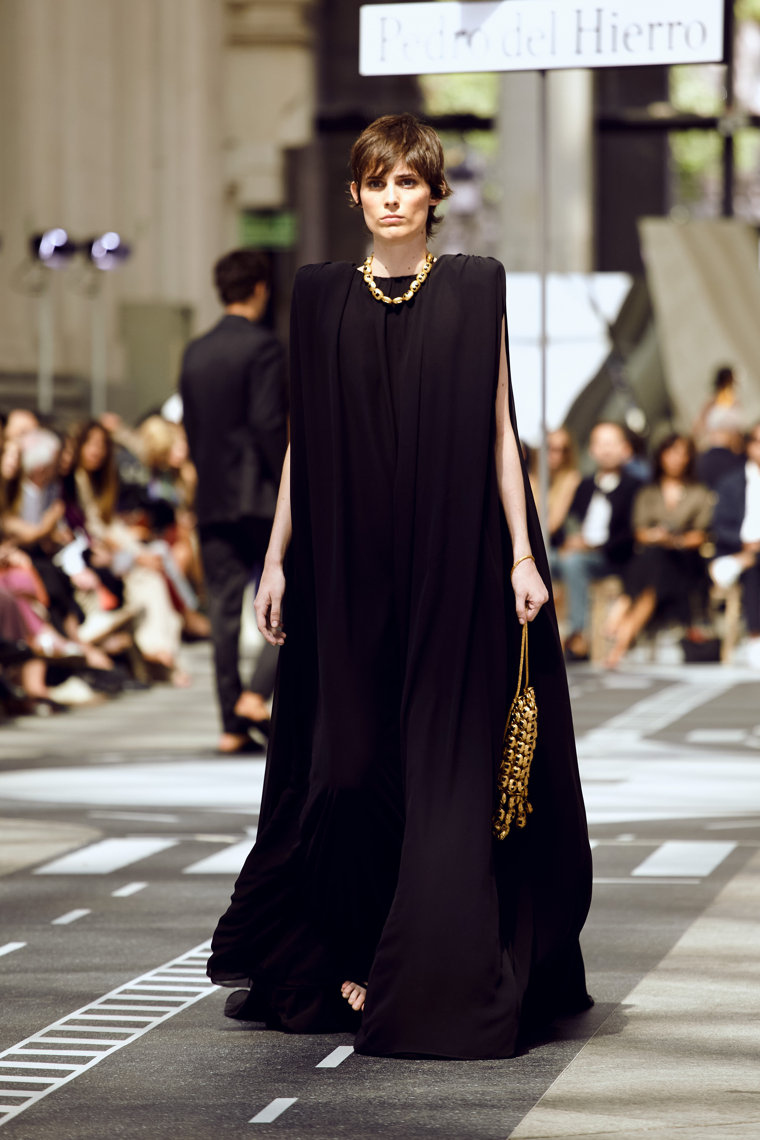 Modelo caminando por la pasarela con vestido negro