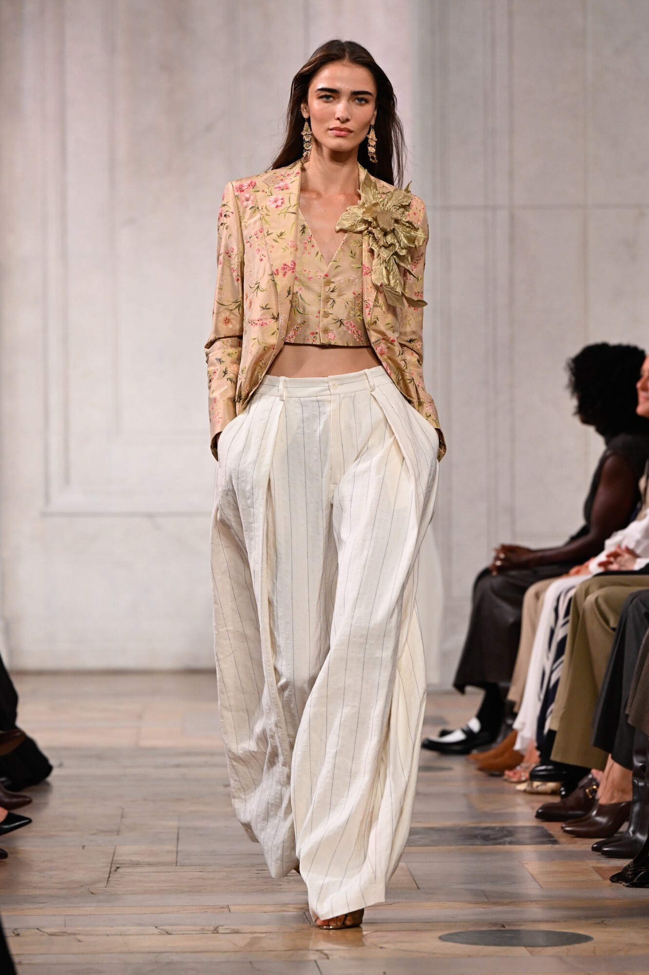 Modelo con chaqueta corta de inspiración floral, torso descubierto y pantalones vaqueros en el desfile de Ralph Lauren Primavera/Verano 2027