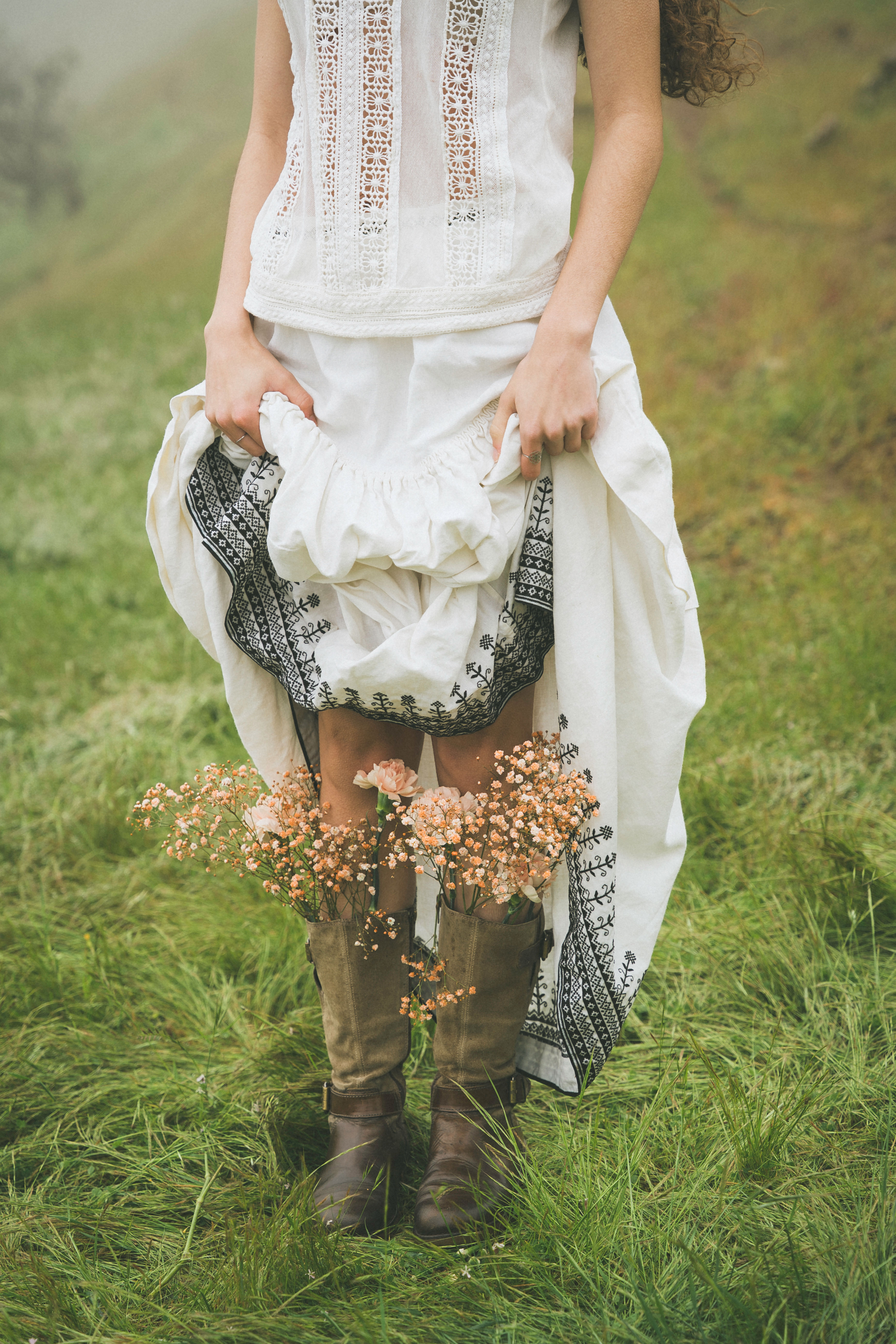 Detalle de las botas de la modelo con flores colocadas entre ellas sobre un campo verde.