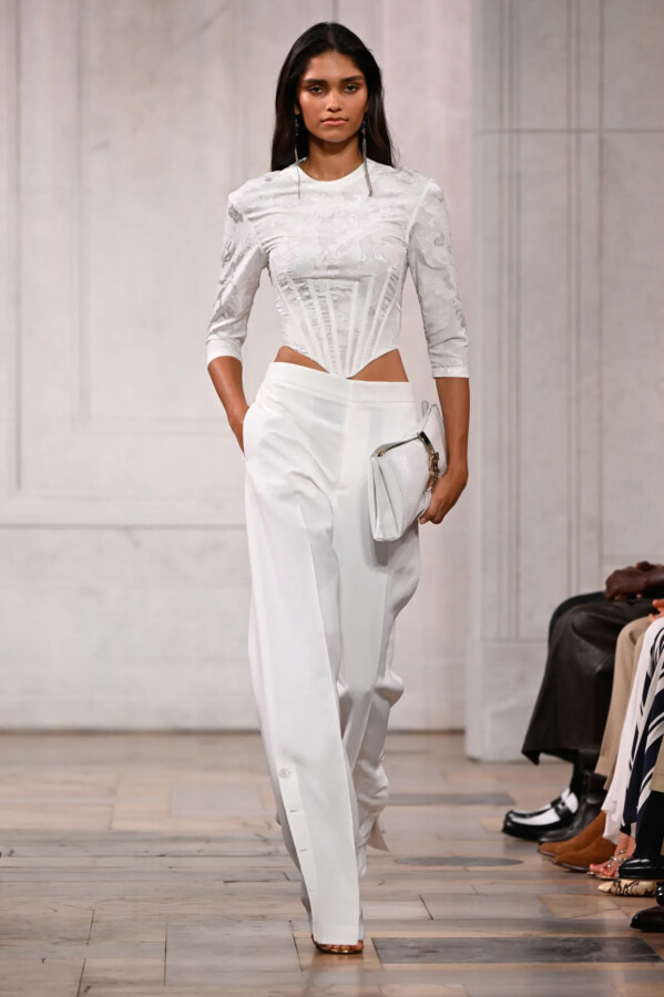 Modelo con camisa de algodón estructurada como un corsé y pantalones blancos de cintura baja en el desfile de Ralph Lauren Primavera/Verano 2027