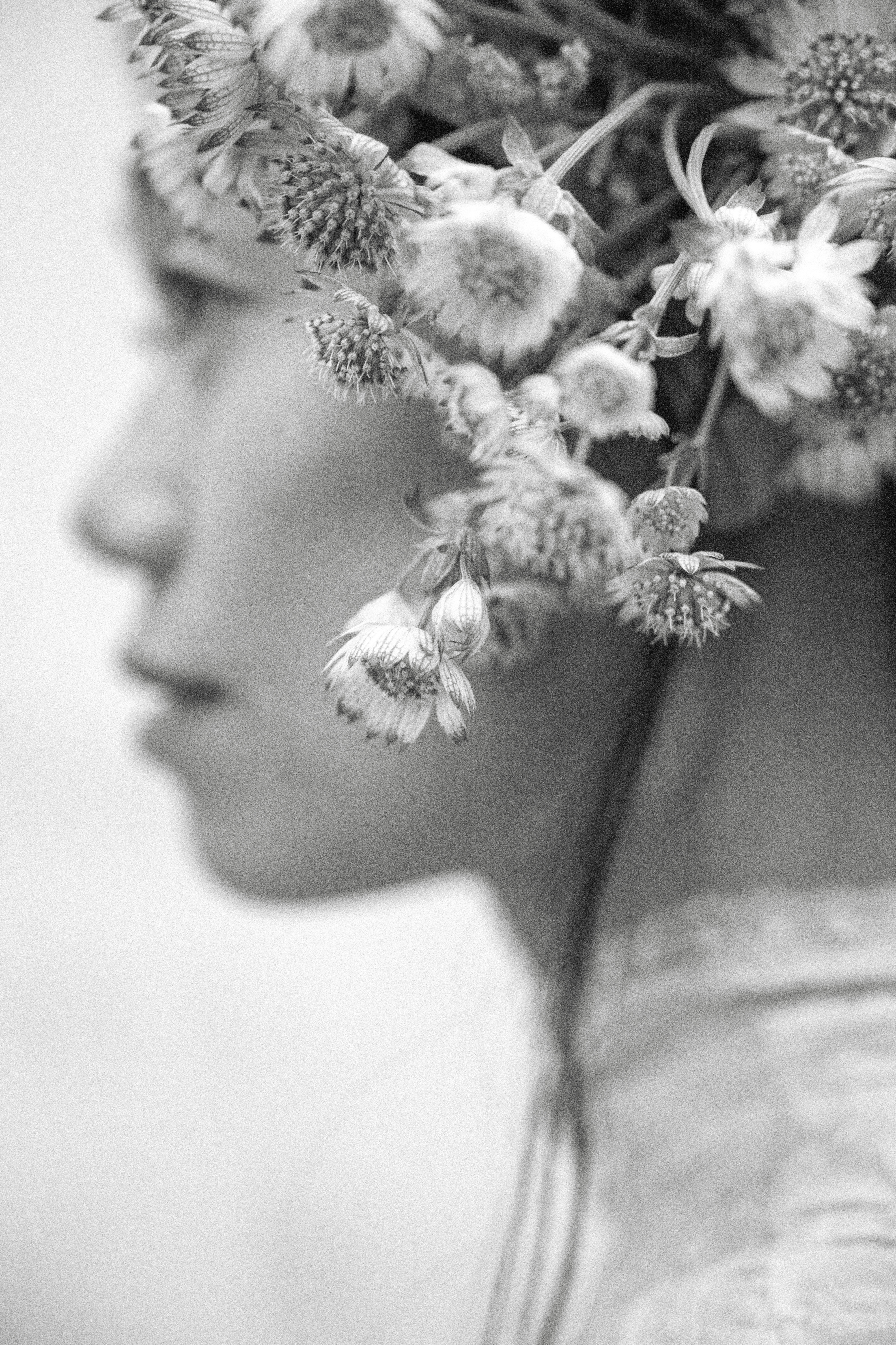 Retrato de perfil de una modelo con tocado floral de gran volumen y luz suave.