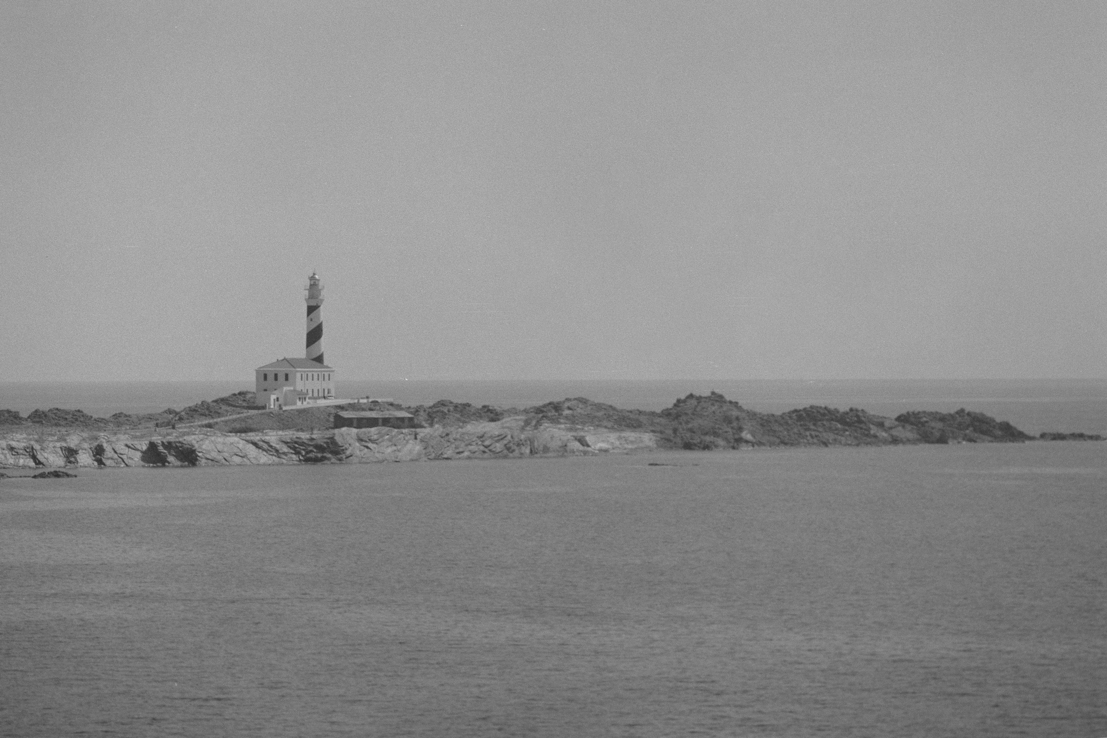 Vista en blanco y negro de un faro y la costa de Menorca en las Islas Baleares
